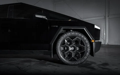 Side view of Tesla Cybertruck equipped with Unplugged Performance 24-inch Cybrhex Wheels in Satin Black, captured in a high-contrast lighting setup to emphasize the truck's angular body and robust wheels.
