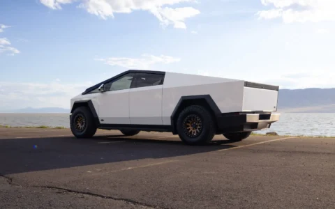 Tesla Cybertruck with custom UP-03 Beadlock Forged Wheels in Satin Bronze finish by Unplugged Performance, highlighting rugged off-road tires and the Cybertruck's futuristic design by a mountain range.