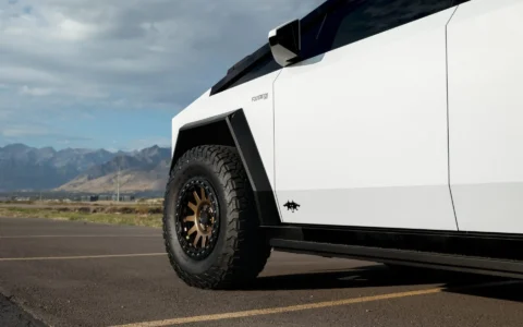 Tesla Cybertruck with custom UP-03 Beadlock Forged Wheels in Satin Bronze finish by Unplugged Performance, highlighting rugged off-road tires and the Cybertruck's futuristic design by a mountain range.